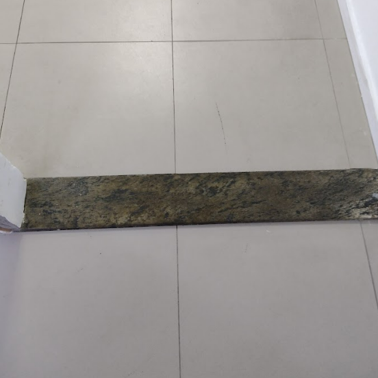 Batente de pedra escura instalado entre dois ambientes de piso claro. Não há faixa colorida ou elemento tátil, dificultando a percepção do desnível — evidenciando ausência de sinalização contrastante.