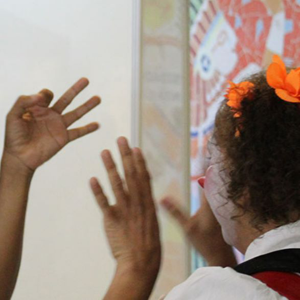 Pessoa intérprete de Libras fazendo contato visual e sinalizando com as mãos para um indivíduo – A imagem mostra um momento de comunicação entre uma pessoa surda e um intérprete, com enfoque no uso expressivo das mãos e do rosto.
