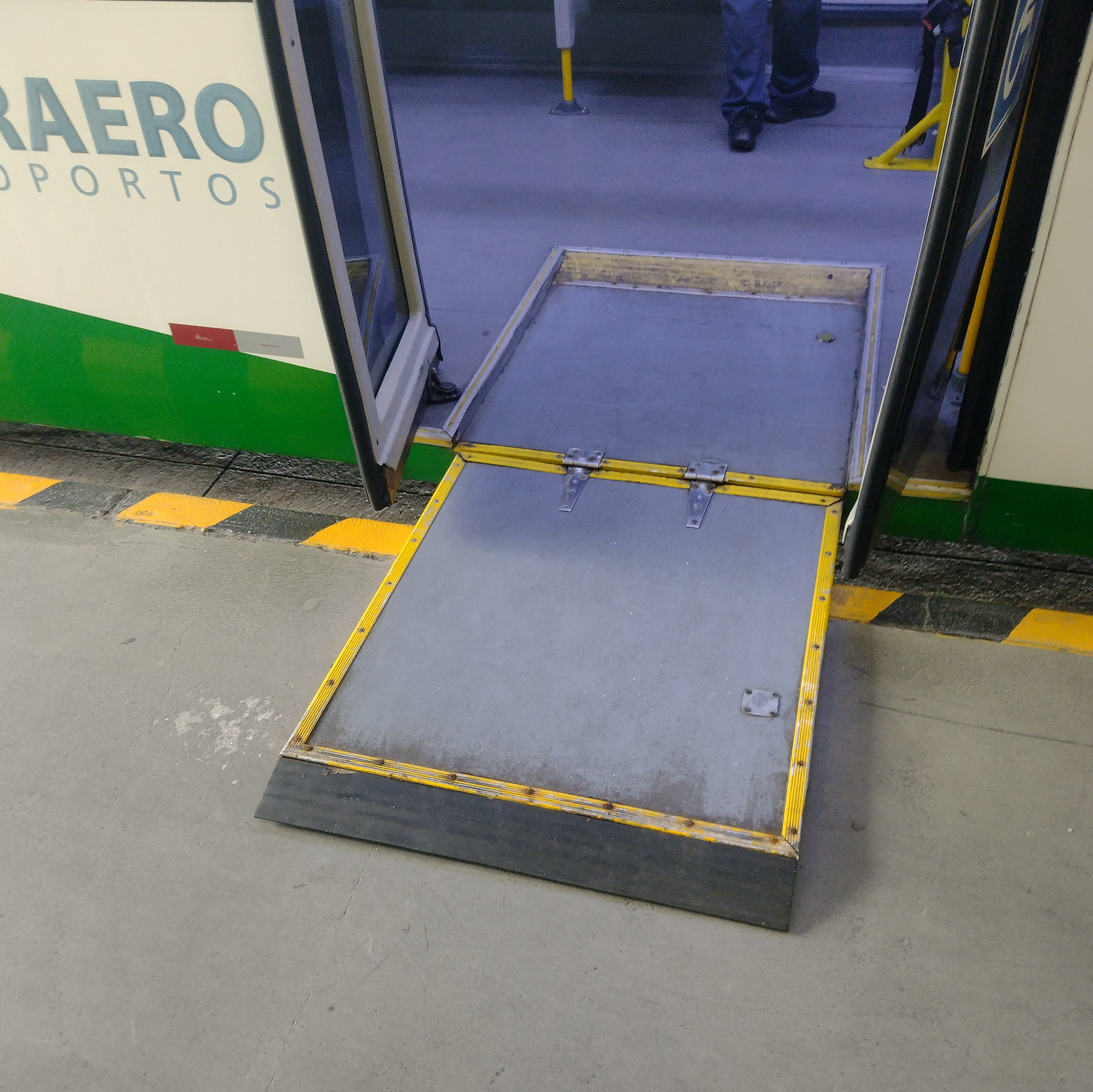 Rampa móvel conectando a porta do ônibus ao piso do terminal, garantindo o embarque e desembarque seguros de passageiros com mobilidade reduzida.