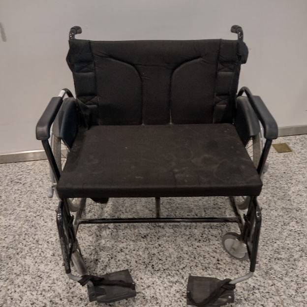 Cadeira de rodas extra larga de transporte, com assento preto acolchoado e dois apoios para os pés, voltada para atender pessoas com obesidade ou mobilidade reduzida.