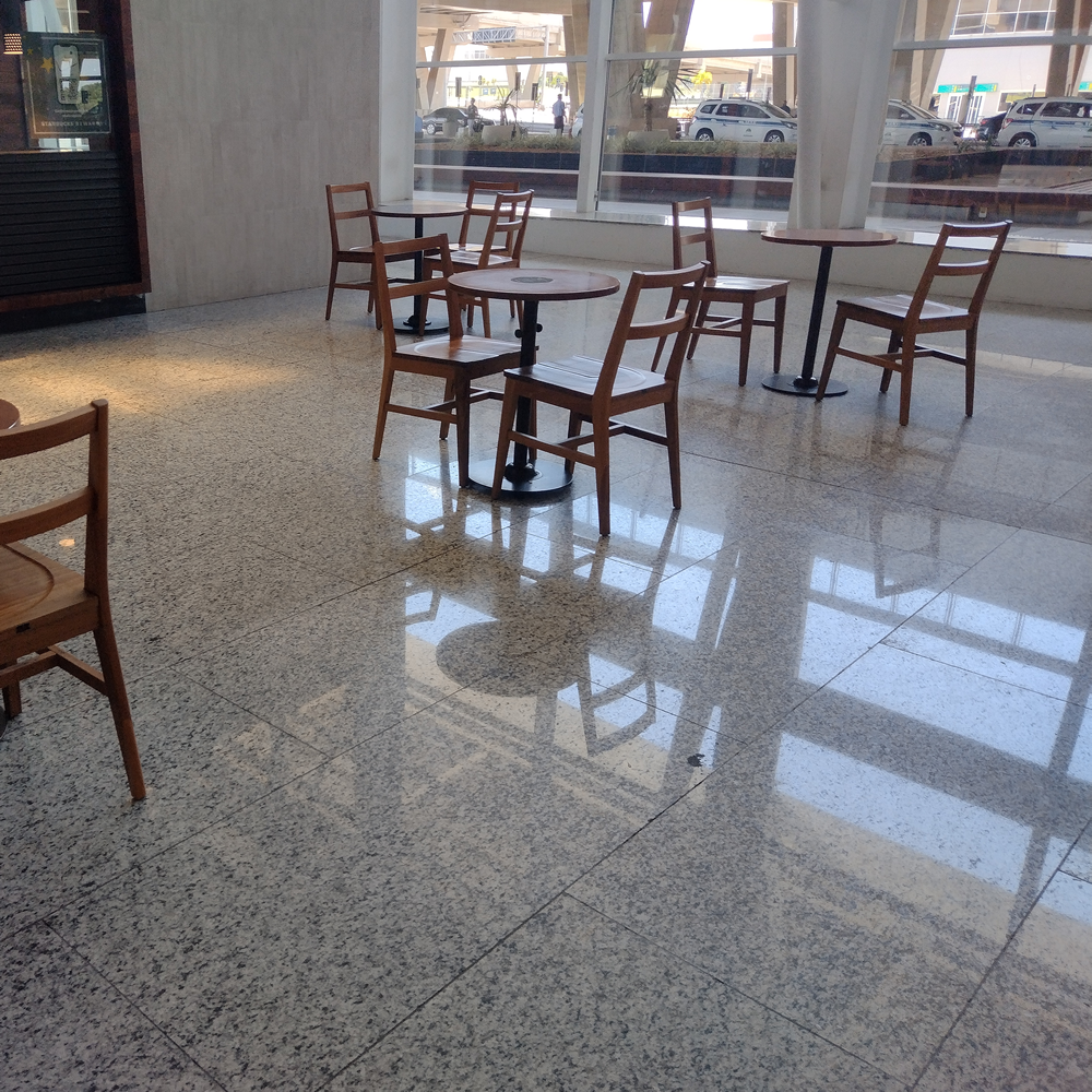 Vista de uma área de alimentação em aeroporto com mesas e cadeiras espaçadas, permitindo a livre circulação de pessoas com mobilidade reduzida.