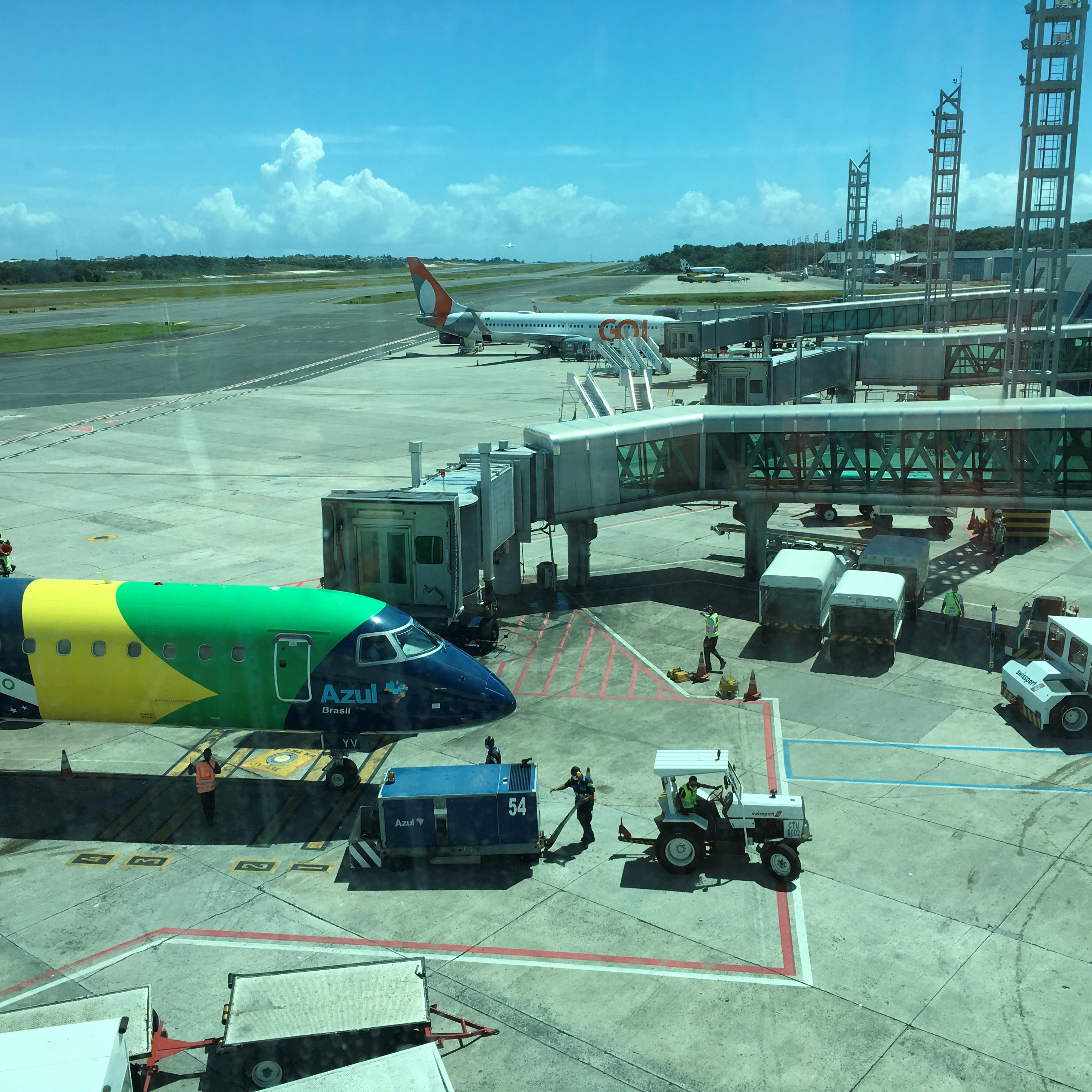 Vista externa de um finger moderno acoplado à porta de uma aeronave. A estrutura metálica e envidraçada liga a área de embarque do aeroporto à aeronave, permitindo acesso direto, plano e coberto.