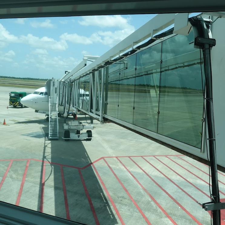 Vista similar à anterior, mostrando um finger laranja da empresa aérea GOL com estrutura translúcida e rampa, também acoplado à aeronave, evidenciando acessibilidade e segurança para o embarque.