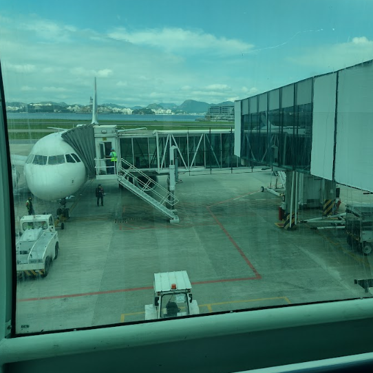 Vista lateral de um finger em operação no aeroporto. A ponte está conectada à porta do avião e se estende até o terminal, com marcações no solo para orientação e segurança operacional.