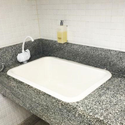 Pia com torneira de fácil acionamento e cuba larga, instalada em bancada rebaixada de granito, própria para lavagem de crianças ou apoio à troca de roupas.