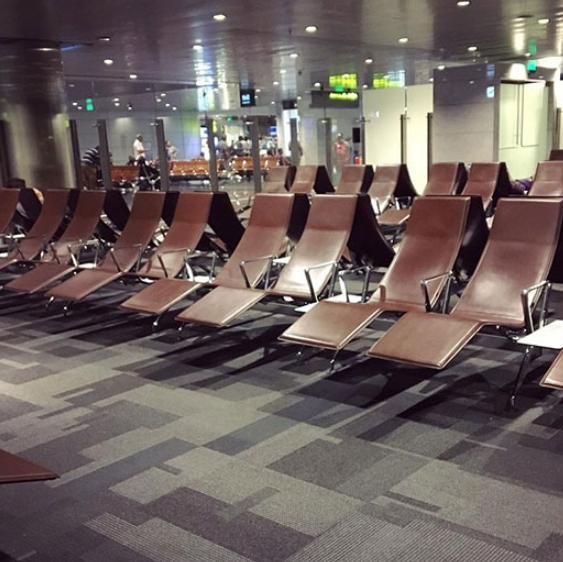Espaço de espera em aeroporto com cadeiras reclinadas, ambiente silencioso e iluminação suave, ideal para descanso.
