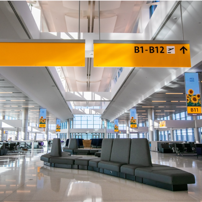 Área ampla em aeroporto com poltronas espaçadas, iluminação natural e poucos estímulos visuais, promovendo tranquilidade.